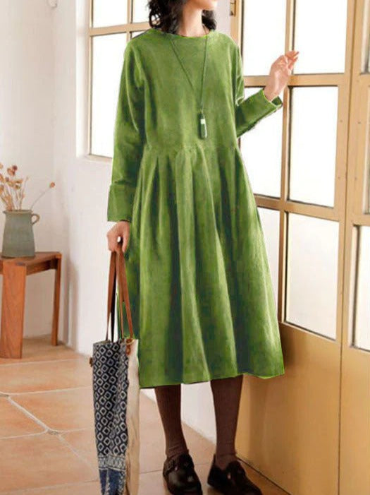 Robe longue vert olive à manches longues, vue trois-quarts debout près fenêtre, robe fluide femme style quotidien
