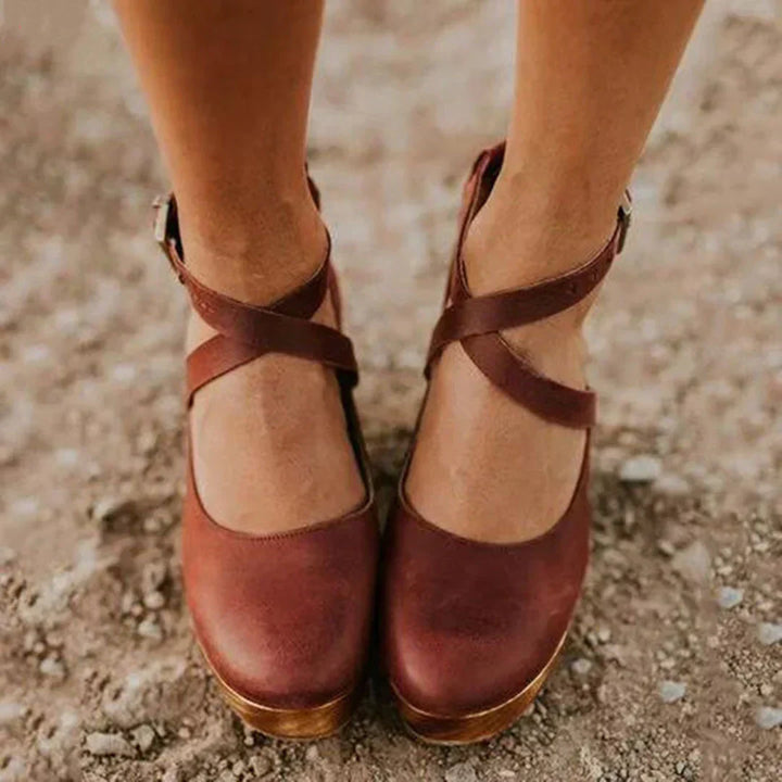 Sandales marron pour femme avec brides croisées et talon épais, portées en extérieur sur sol naturel