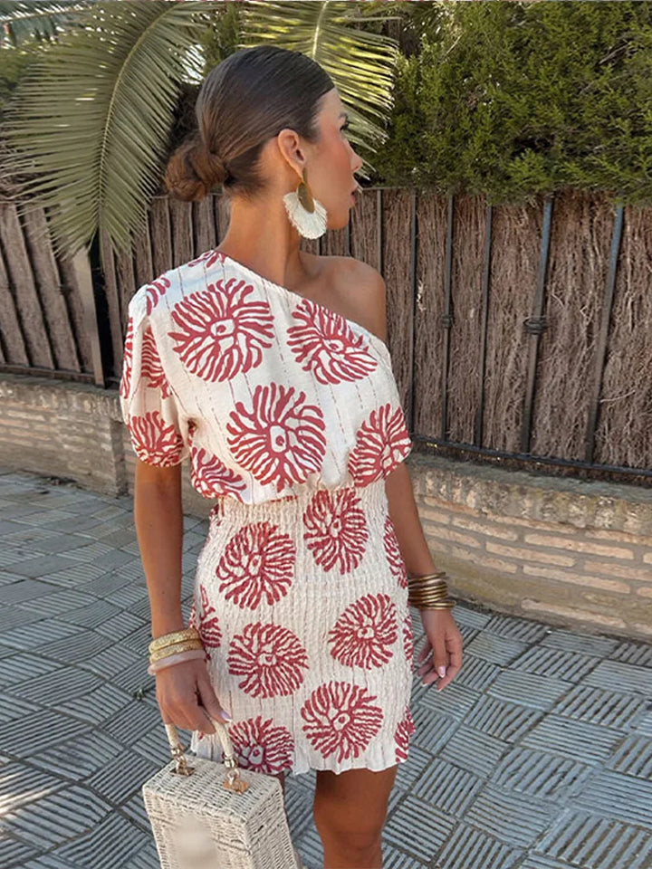 Vue latérale d’une robe blanc/rouge à épaule asymétrique, imprimé floral et style chic d’été