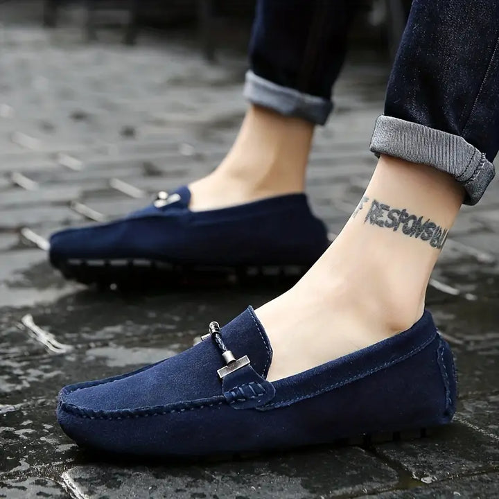 Mocassins bleu pour homme avec détail métallique sur le dessus, portés avec pantalon foncé