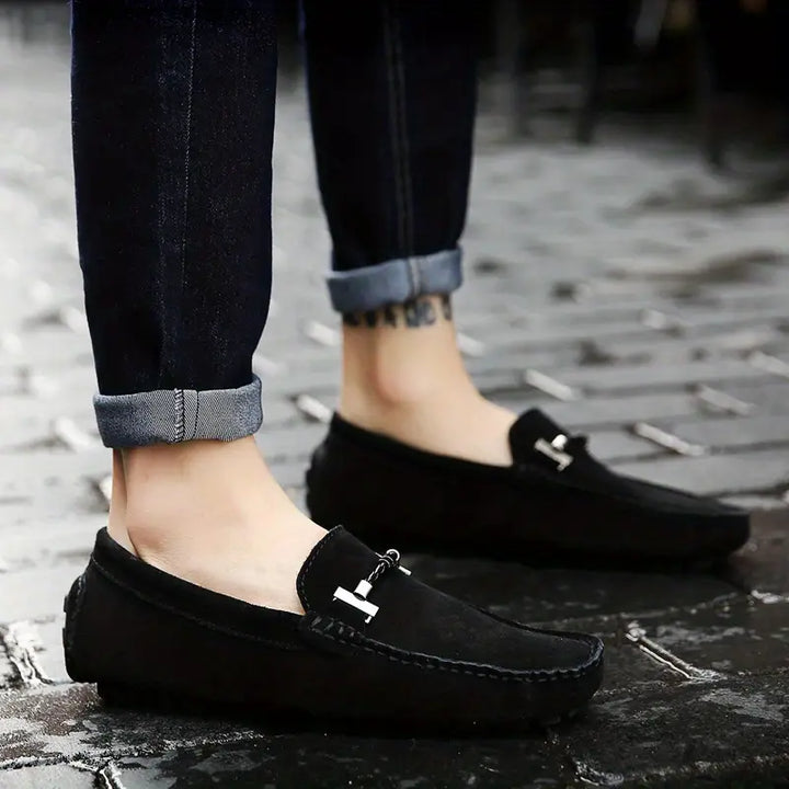 Homme portant des mocassins noir élégants sur sol pavé, design moderne et confortable