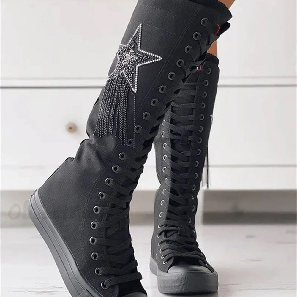 Bottes sneakers noires portées de trois-quarts, mettant en valeur la tige montante, les lacets et l'étoile décorative.