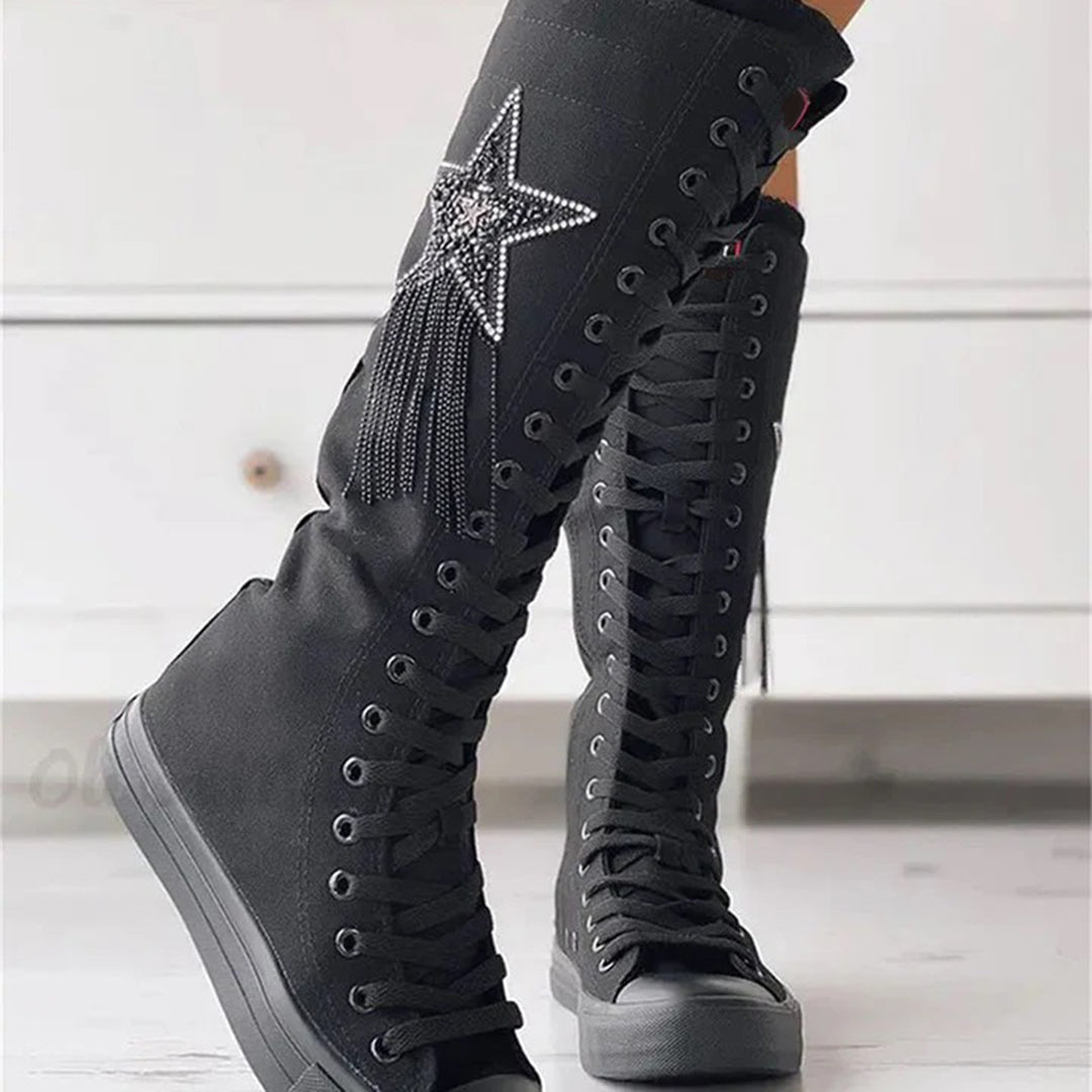 Bottes sneakers noires portées de trois-quarts, mettant en valeur la tige montante, les lacets et l'étoile décorative.