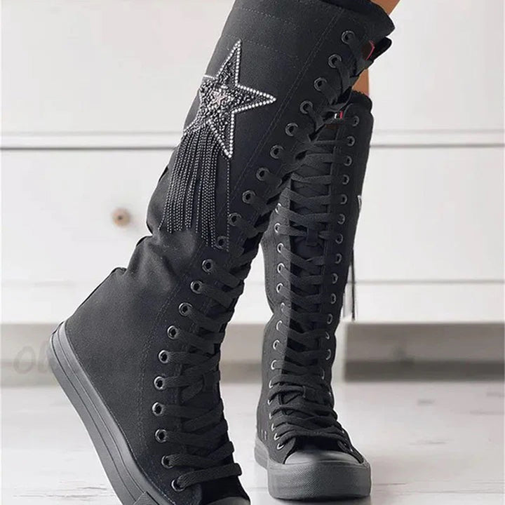 Bottes sneakers noires portées de trois-quarts, mettant en valeur la tige montante, les lacets et l'étoile décorative.