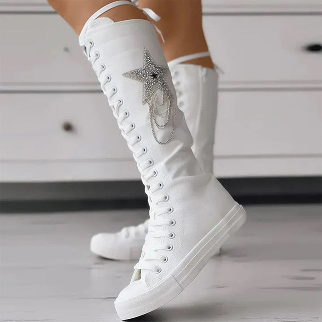 Vue latérale des bottes sneakers blanches avec lacets, semelle épaisse et étoile décorative.