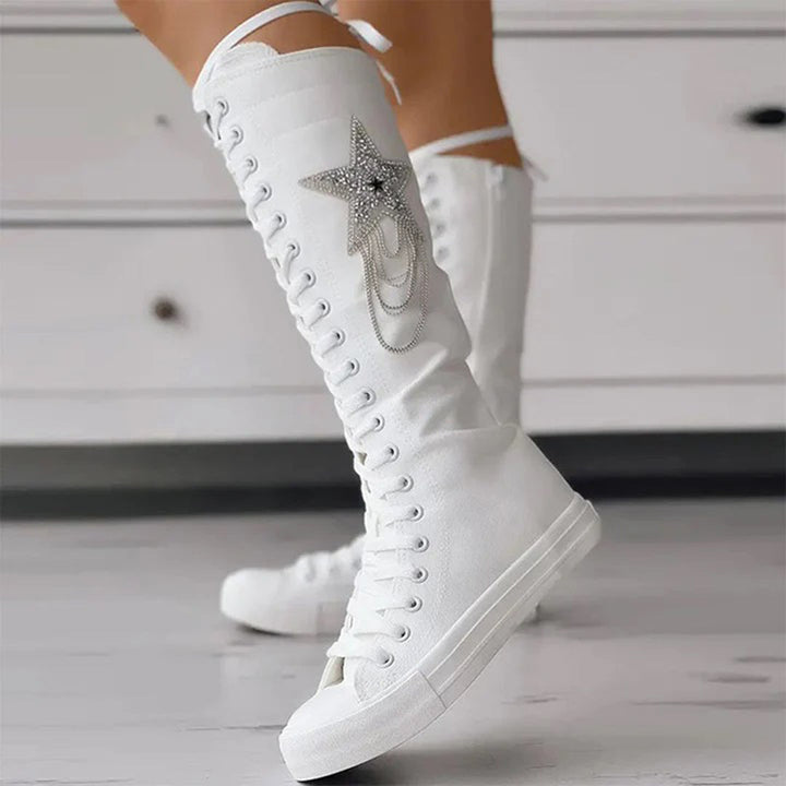 Vue latérale des bottes sneakers blanches avec lacets, semelle épaisse et étoile décorative.