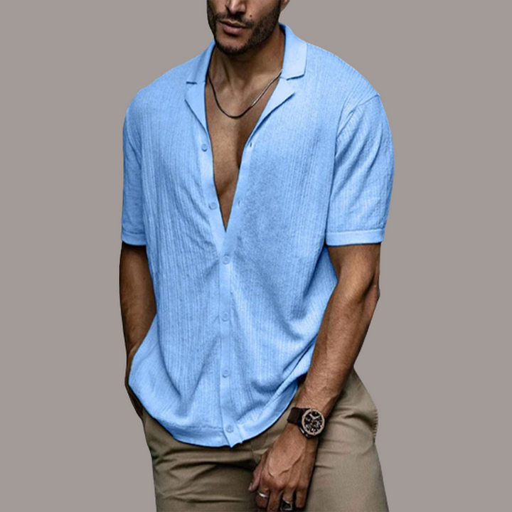 Chemise d'été en lin bleue pour homme avec col ouvert, manches courtes et coupe décontractée portée avec un pantalon beige