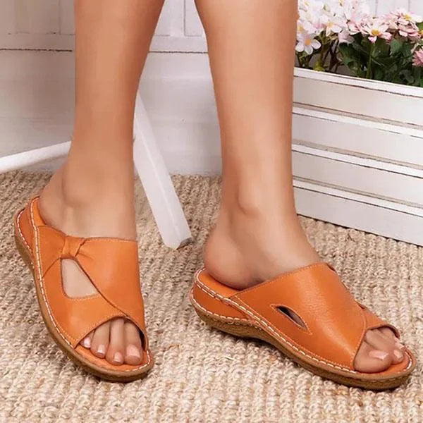 Sandales décontractées jaune orangé pour femme portées de face, avec brides croisées, détails ajourés et semelle plate confortable.