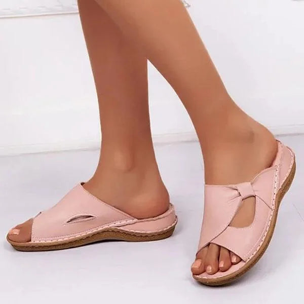 Sandales décontractées roses pour femme portées de profil, avec brides croisées, détails ajourés et semelle plate légère.