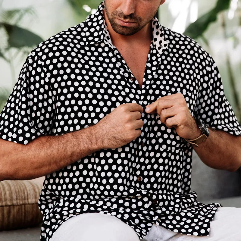 Chemise imprimée noire à manches courtes pour homme avec motif géométrique blanc portée de manière décontractée en extérieur