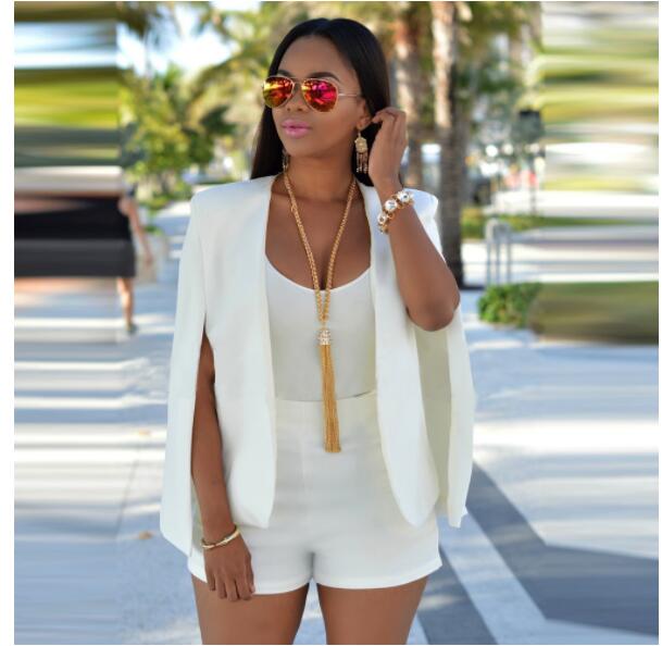 Femme portant un cape manteau blazer blanc avec coupe ample, top blanc et short assorti en extérieur