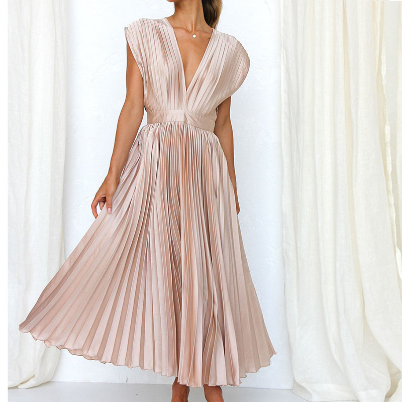 Robe longue champagne à col en V portée de trois-quarts, avec taille marquée et jupe plissée évasée.