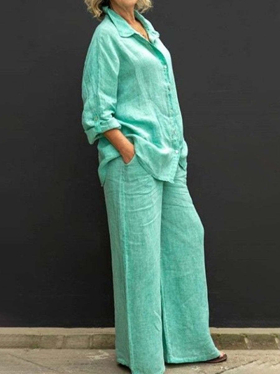 Ensemble femme vert en coton et lin composé d’une chemise ample à manches longues et d’un pantalon large, porté de profil avec les mains dans les poches.