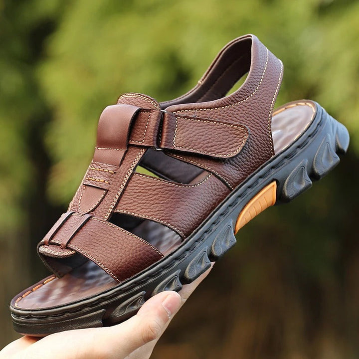 Paire de sandales orthopédiques marron pour homme tenue à la main, avec bout ouvert et semelle épaisse