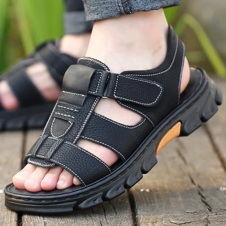 Sandales orthopédiques noir portées en extérieur, design ouvert avec brides réglables et semelle de marche robuste
