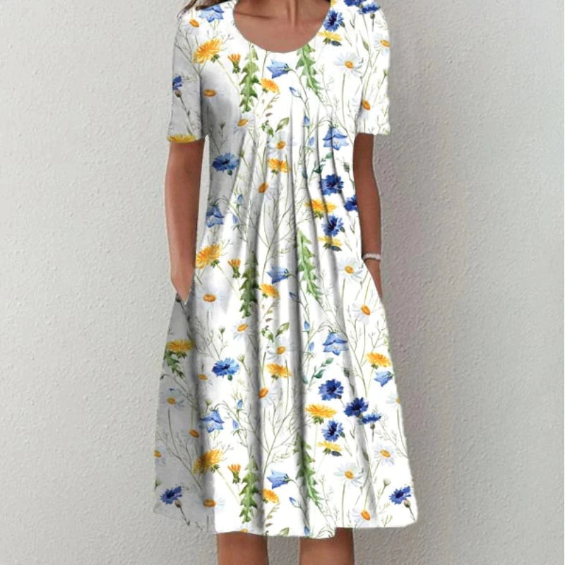 Robe d'été évasée blanche avec imprimé floral jaune et bleu, portée de face avec une silhouette légère et féminine.