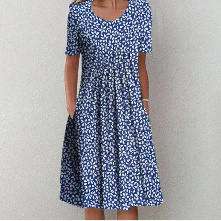 Robe d'été bleue à imprimé floral pour femme, portée de face avec une coupe évasée et des manches courtes.