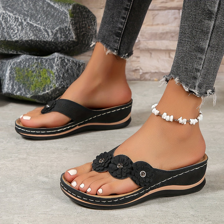 Profil de sandales orthopédiques noir pour femme avec détail floral et semelle ergonomique