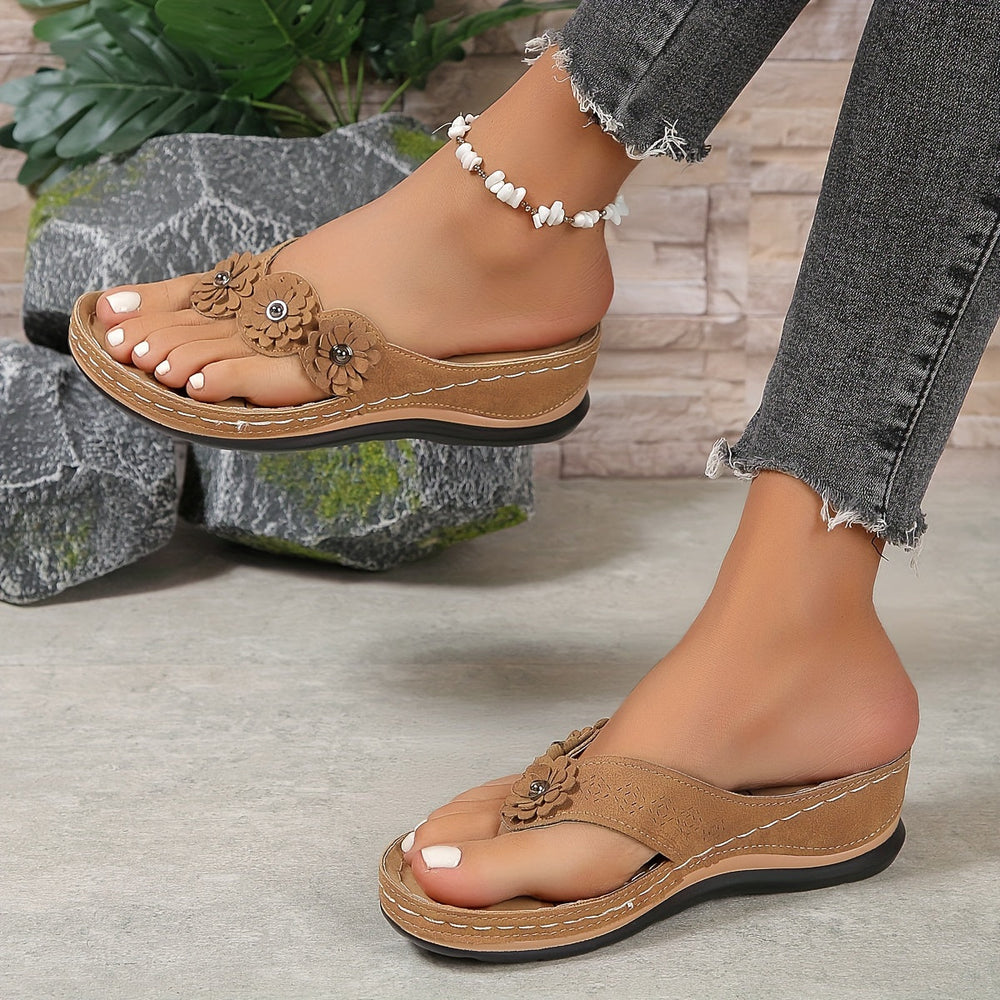 Femme portant des sandales orthopédiques marron à entredoigt avec détail floral et semelle épaisse