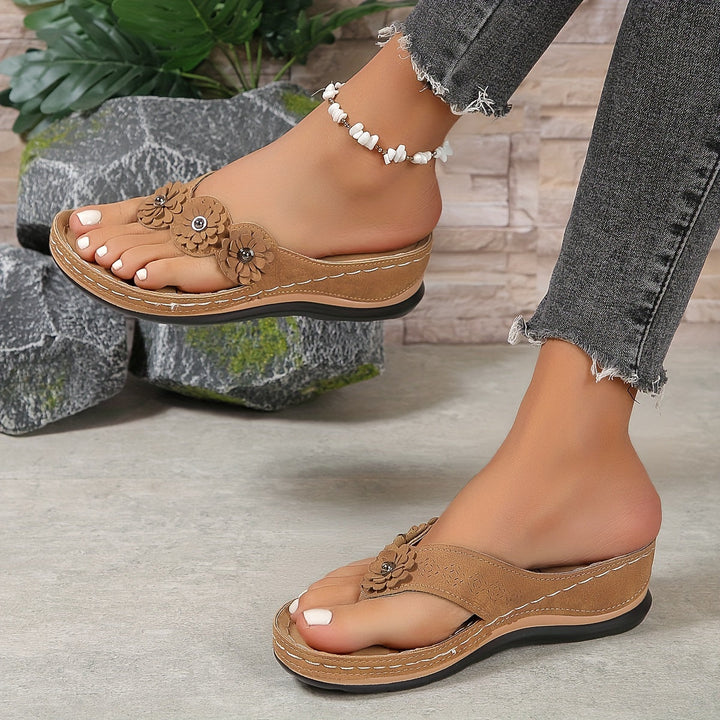 Femme portant des sandales orthopédiques marron à entredoigt avec détail floral et semelle épaisse