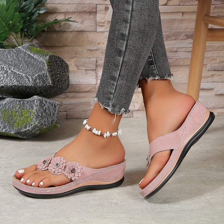 Femme portant des sandales orthopédiques rose avec semelle compensée et détails brillants sur la bride
