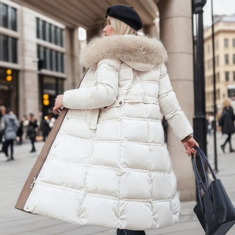 Doudoune longue Blanc femme, vue de profil en ville, capuche relevée, coupe oversize matelassée jusqu’aux mollets