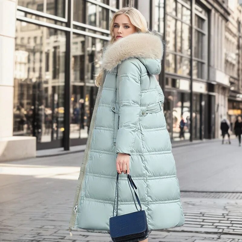 Doudoune longue femme Bleu clair, vue de profil en ville avec sac bleu, capuche et col effet fourrure, manteau matelassé hiver