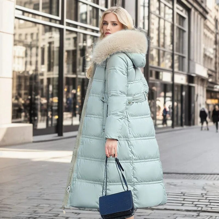 Doudoune longue femme Bleu clair, vue de profil en ville avec sac bleu, capuche et col effet fourrure, manteau matelassé hiver