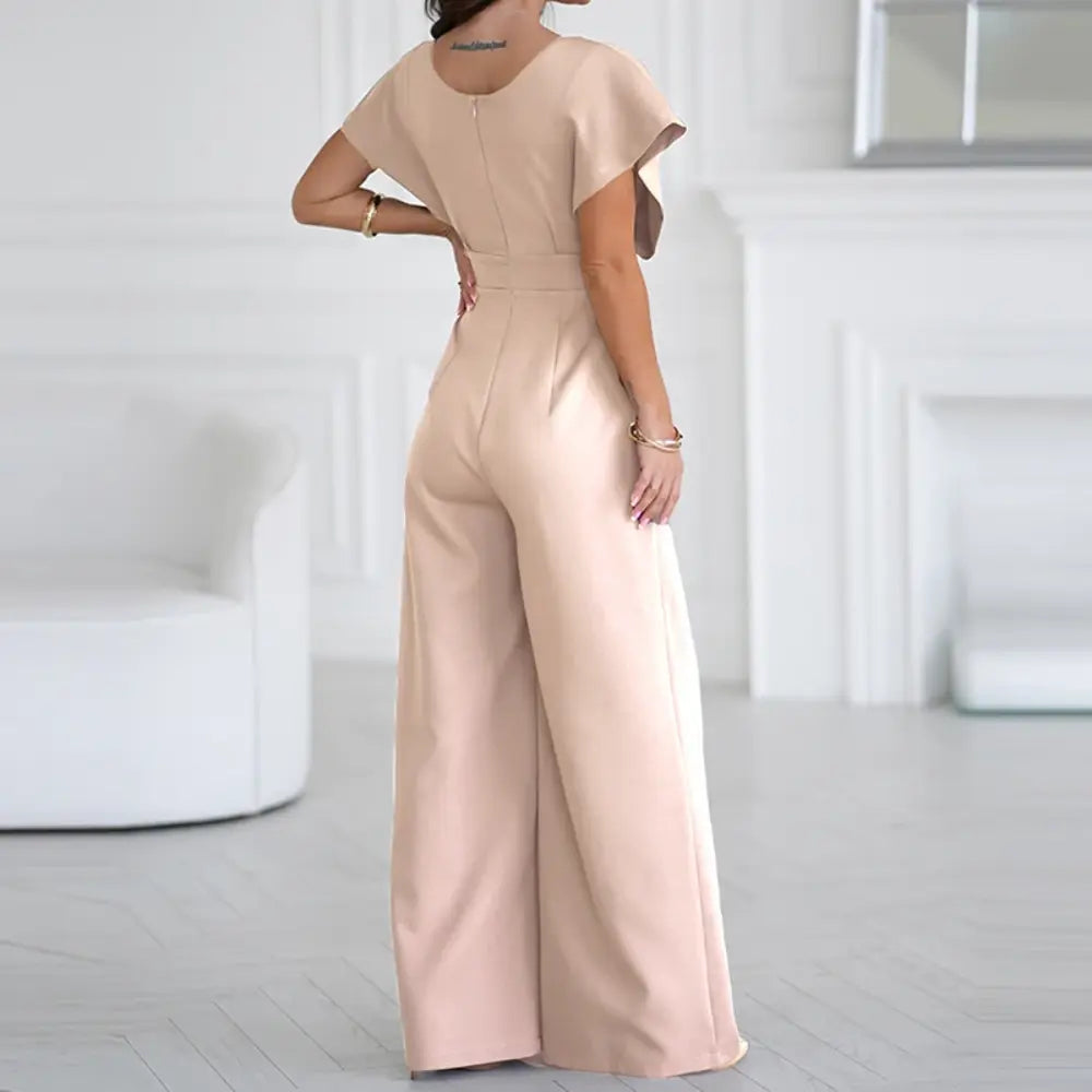 Femme portant une combinaison rose élégante avec taille marquée et coupe fluide confortable