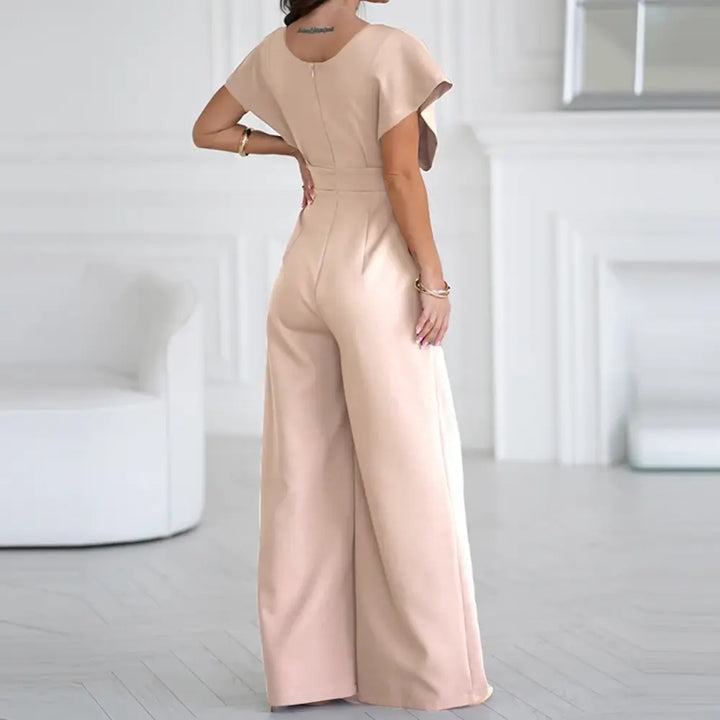 Femme portant une combinaison rose élégante avec taille marquée et coupe fluide confortable