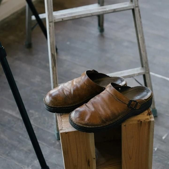 Pantoufle orthopédique en cuir beige portée lors d'une utilisation quotidienne près d'une chaise.