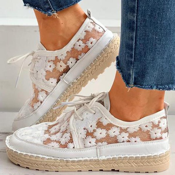 Chaussures orthopédiques blanches portées en marchant, montrant le motif floral ajouré et la semelle épaisse.
