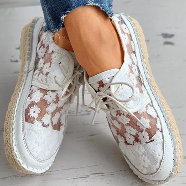 Chaussures orthopédiques blanches avec motif floral vues de dessus, mettant en valeur les lacets et le design respirant.