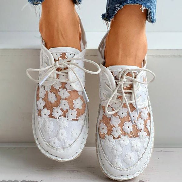 Vue de face des chaussures orthopédiques blanches avec motif floral portées sous un jean.