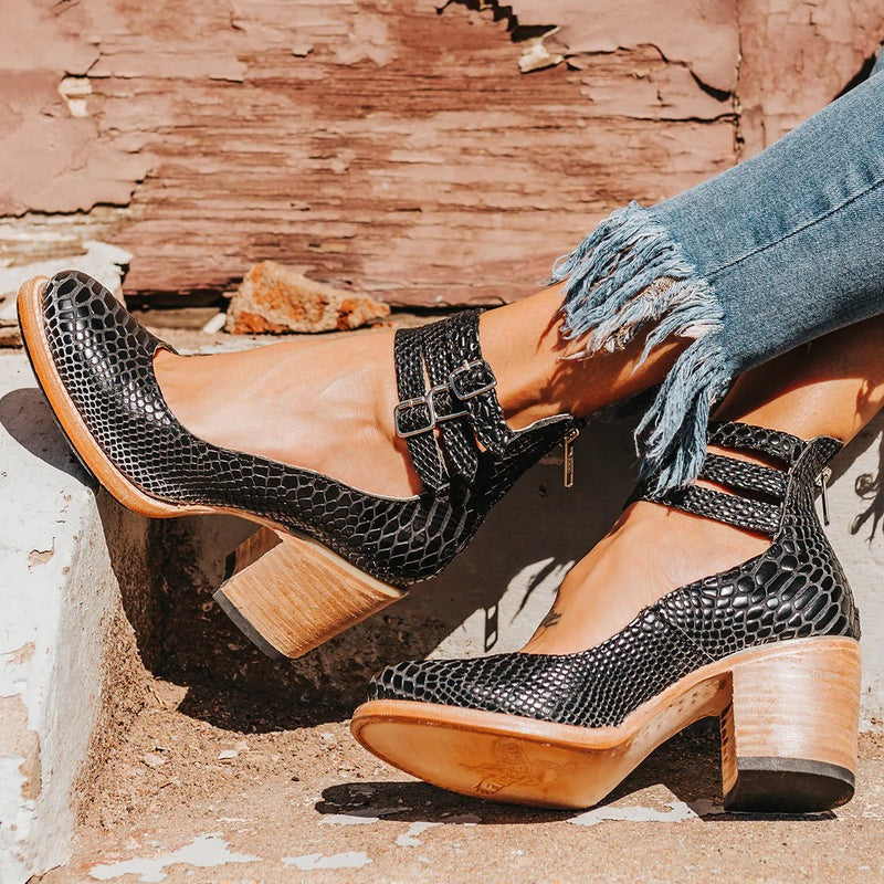 Bottines noires avec texture effet serpent et talon en bois, photographiées sur fond clair