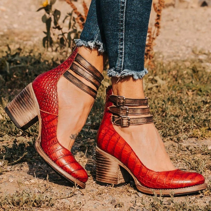 Bottines rouge foncé avec texture croco et talon carré sur fond neutre