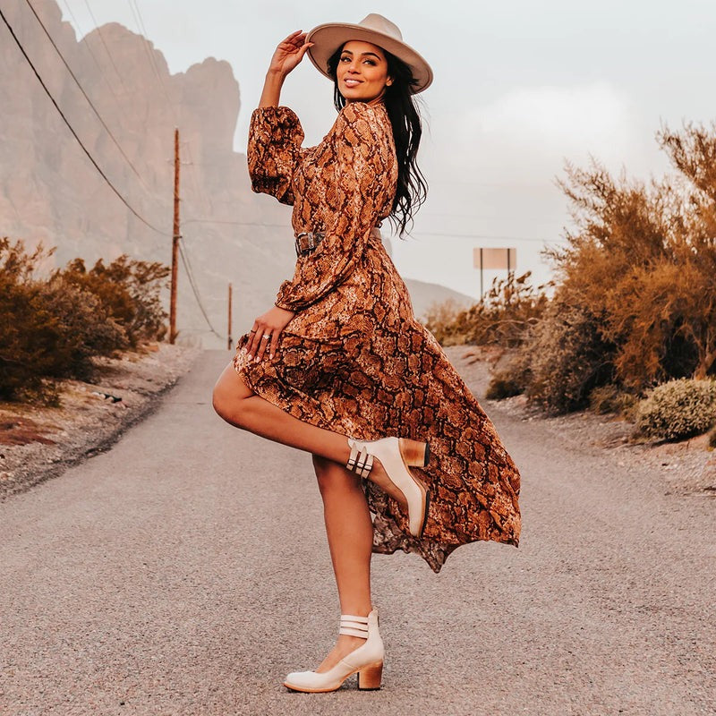 Femme portant des bottines marron dans un décor extérieur, tenue bohème avec robe longue