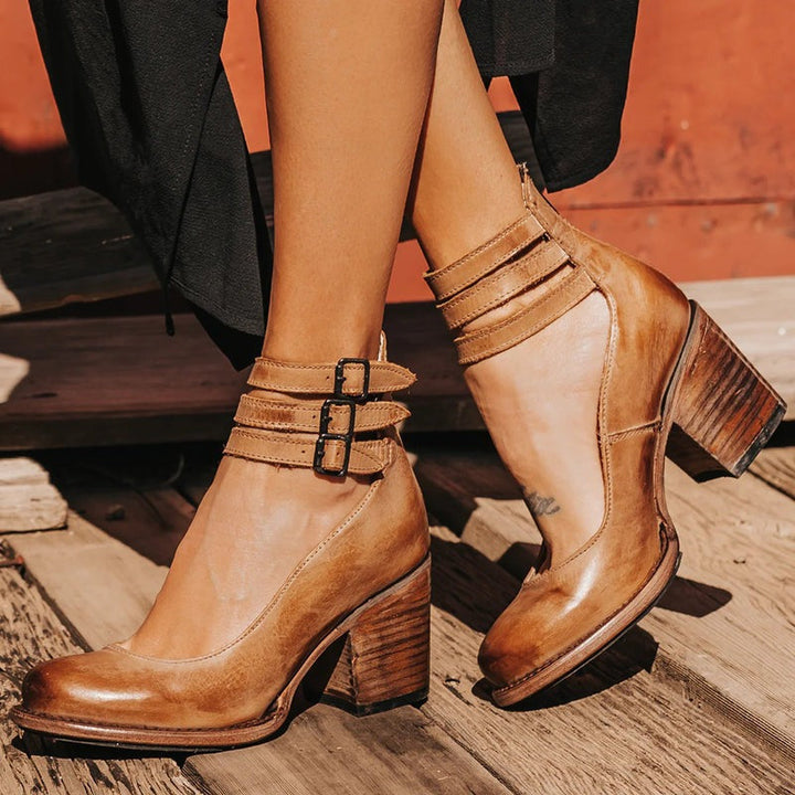 Femme marchant avec des bottines marron à talon carré, avec plusieurs brides décoratives autour de la cheville