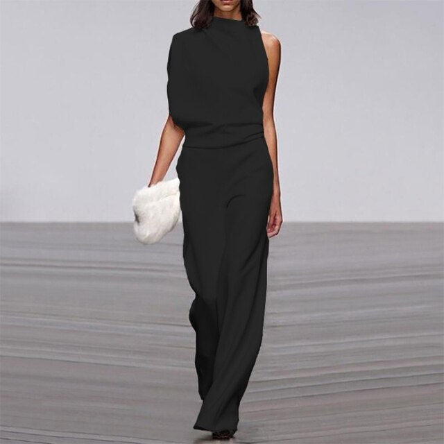 Combinaison noire élégante pour femme portée de face, avec un haut sans manches, une taille marquée et un pantalon long à jambes larges.