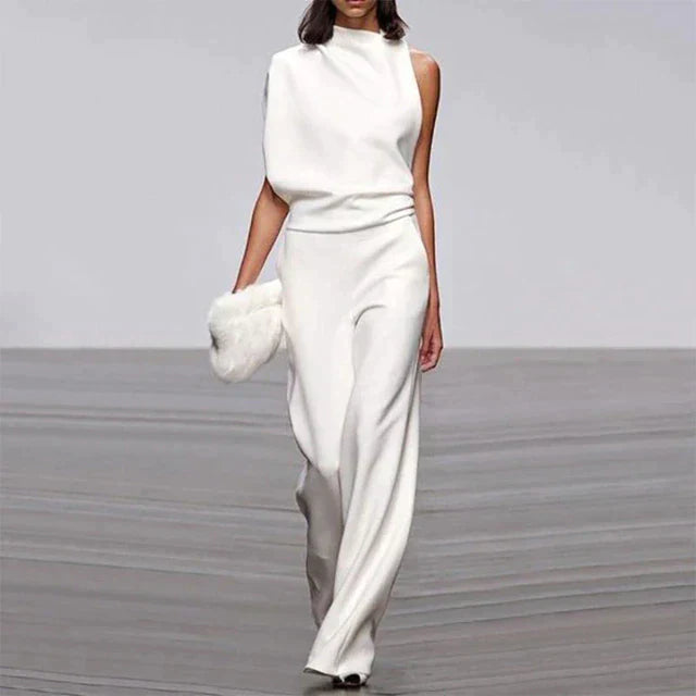 Combinaison blanche élégante pour femme portée de face, avec un haut sans manches, une taille marquée et un pantalon long à jambes larges.