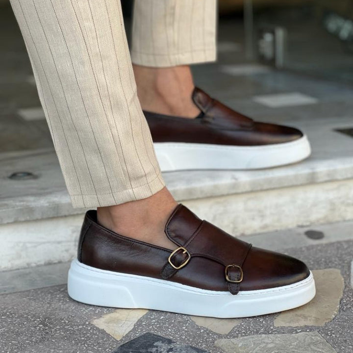 Mocassins en cuir marron pour homme avec double boucle métallique, semelle blanche épaisse et pantalon beige