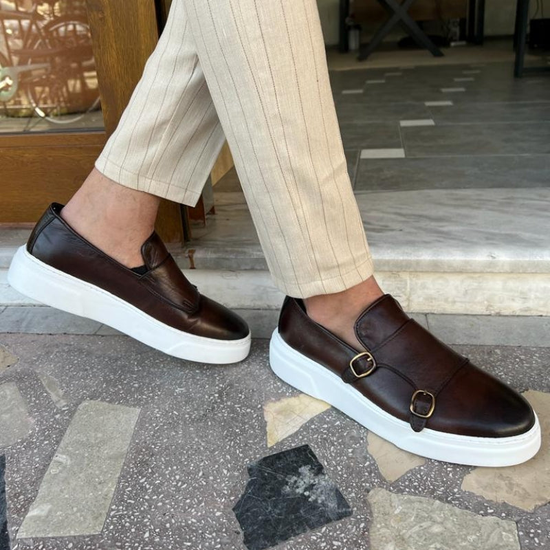 Homme portant des mocassins en cuir marron avec semelle blanche, vus en marchant sur sol extérieur