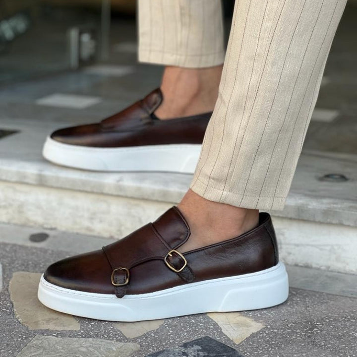 Vue latérale de mocassins en cuir marron avec détails métalliques, semelle blanche et coupe moderne