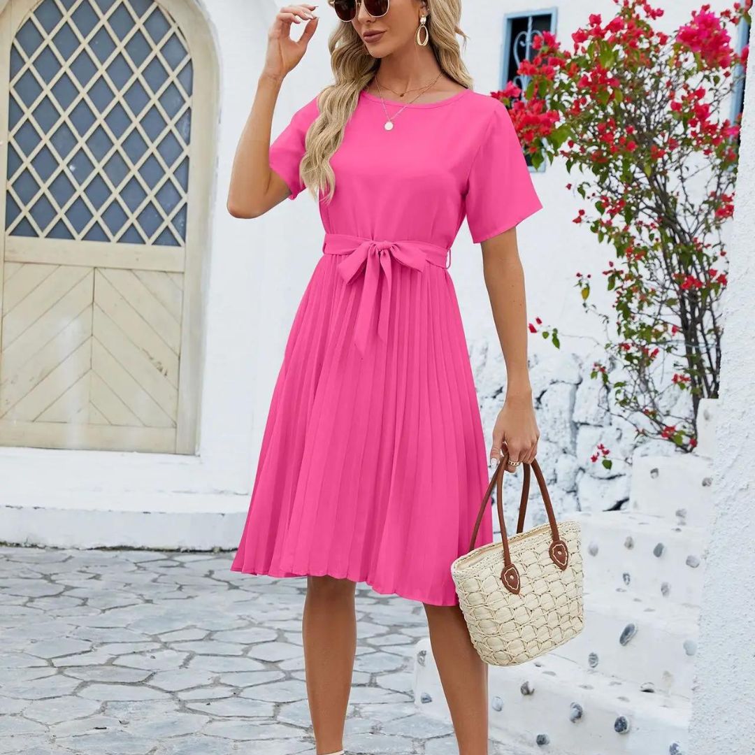 Vue de face d’une robe rose avec col en V, ceinture assortie et jupe fluide