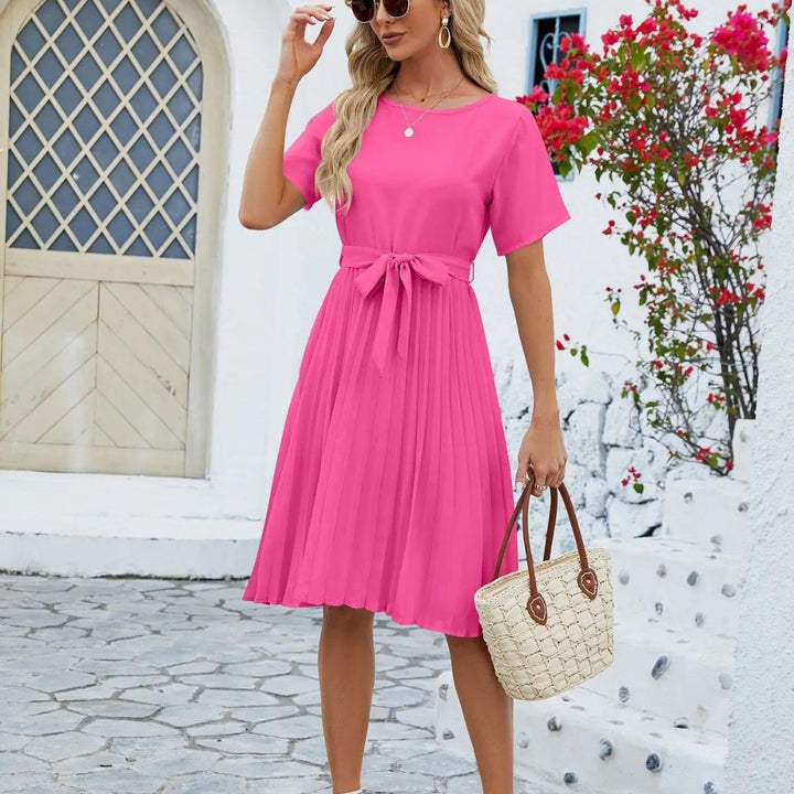Vue de face d’une robe rose avec col en V, ceinture assortie et jupe fluide