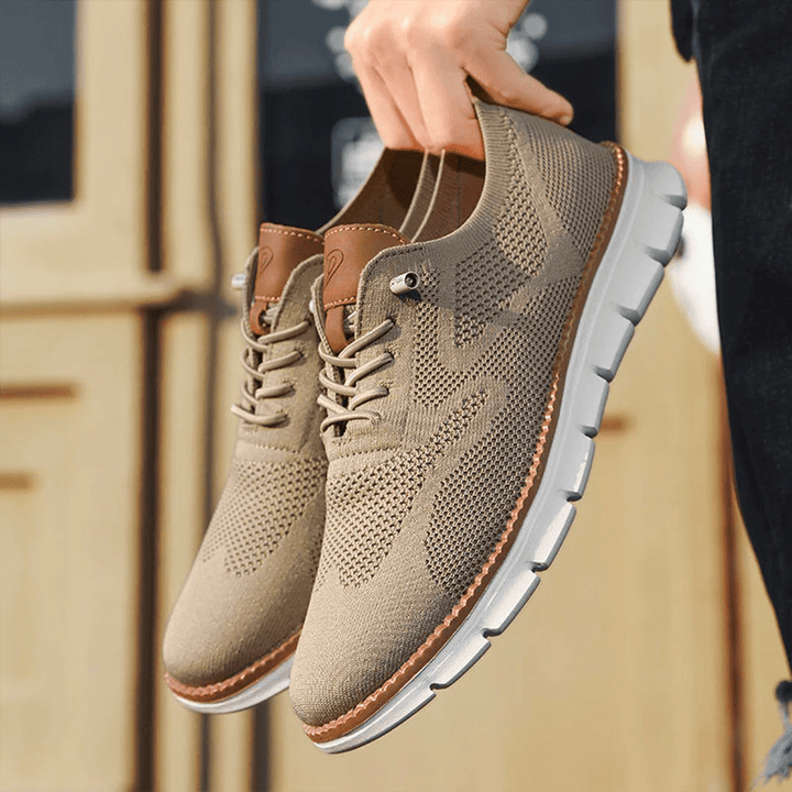 Homme tenant des baskets gris légères avec lacets et semelle confortable pour la marche