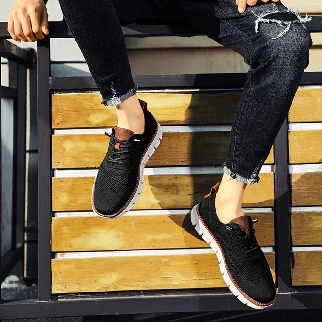 Homme portant des baskets noir confortables avec jean, assis sur des marches en extérieur