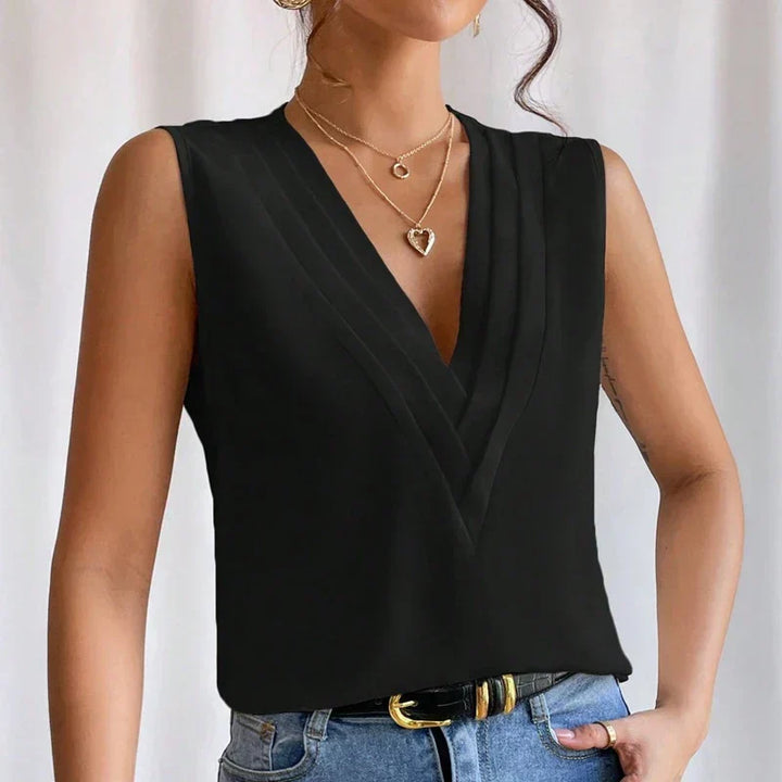 Femme portant une blouse noir sans manches avec jean bleu, sac blanc et style élégant