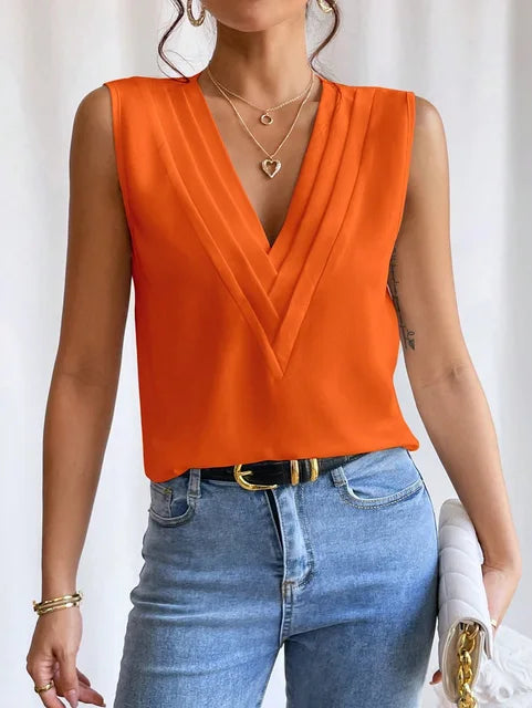 Femme portant une blouse orange fluide sans manches avec col croisé et jean bleu clair