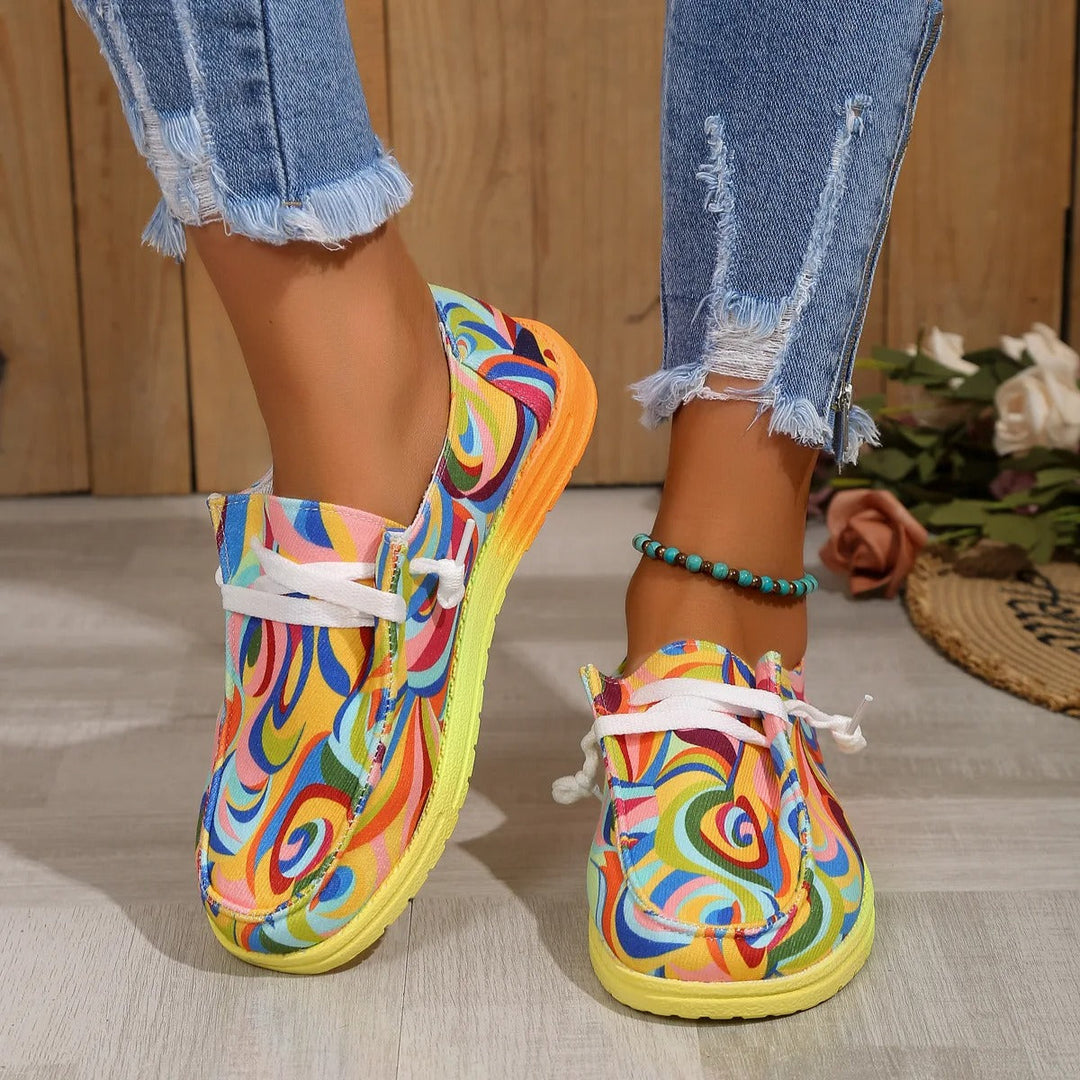 Chaussures de sport colorées jaune pour femme portées avec un jean, imprimé multicolore artistique et semelle confortable antidérapante